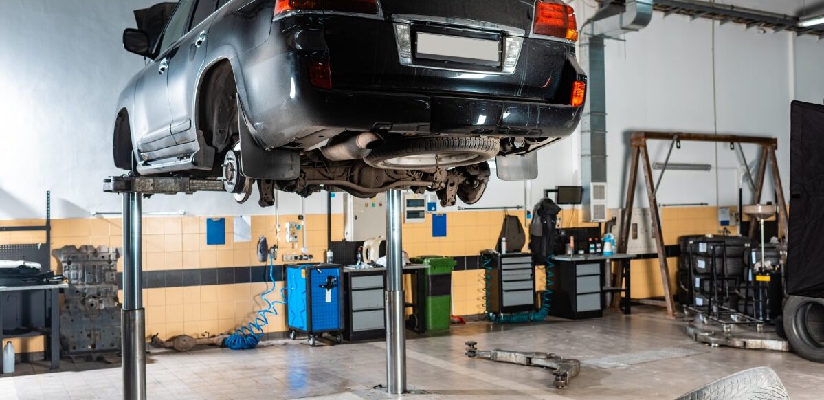 modern black car raised on car lift in workshop