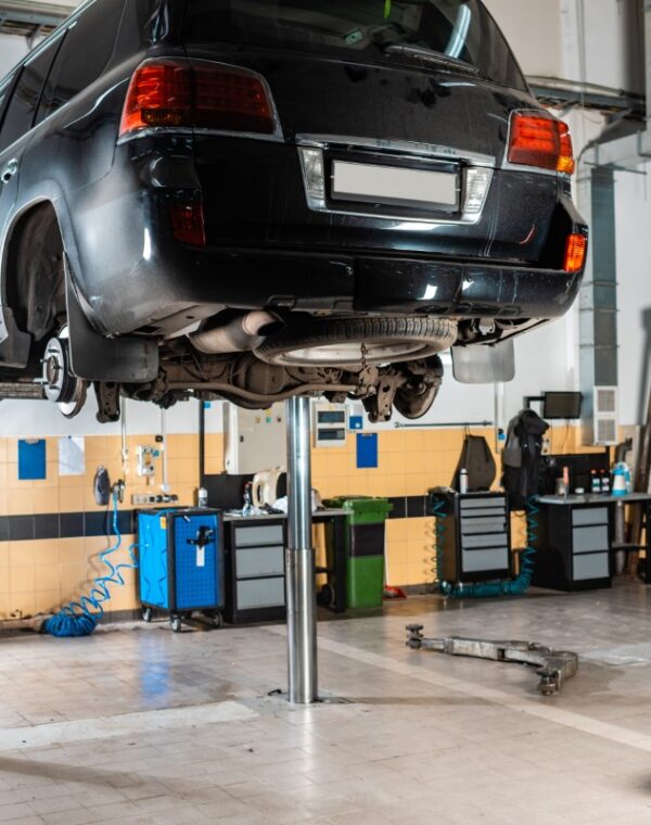 modern black car raised on car lift in workshop